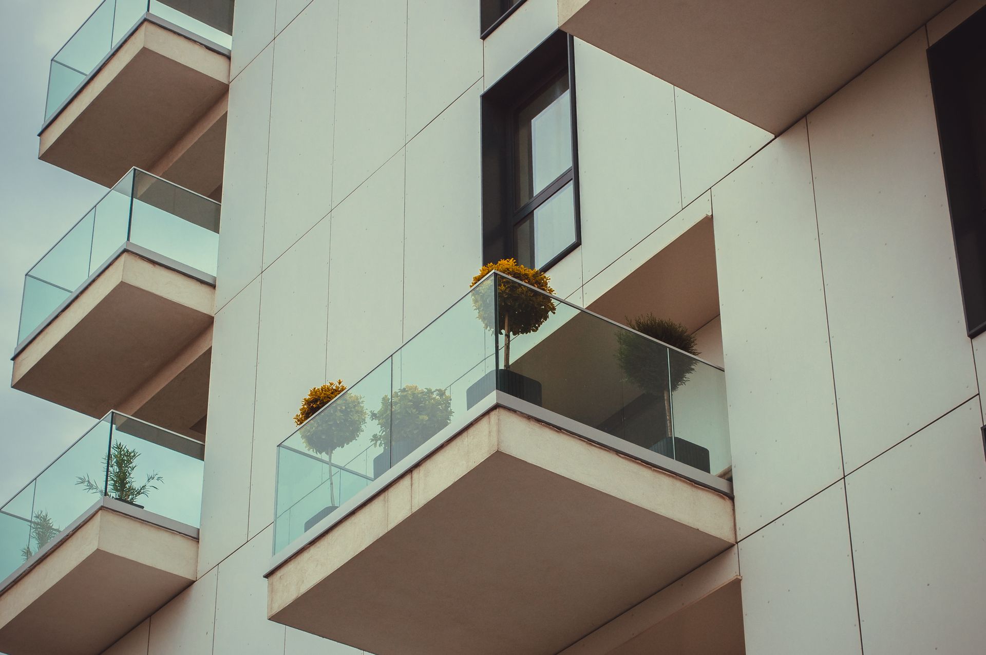 Modern residential balcony with clear glass railings and urban surroundings