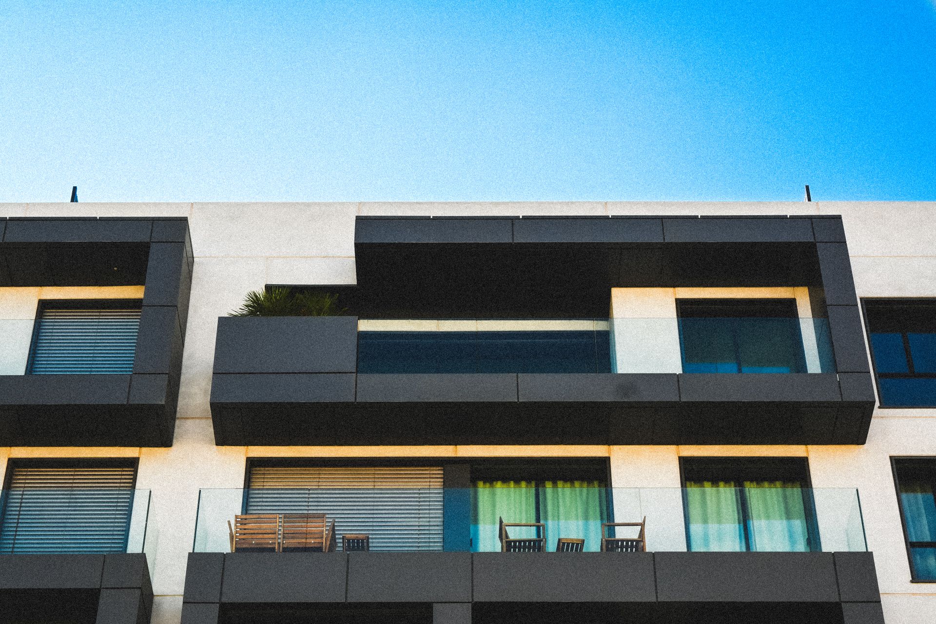 Clear glass balcony railing with clean panels overlooking a residential outdoor space