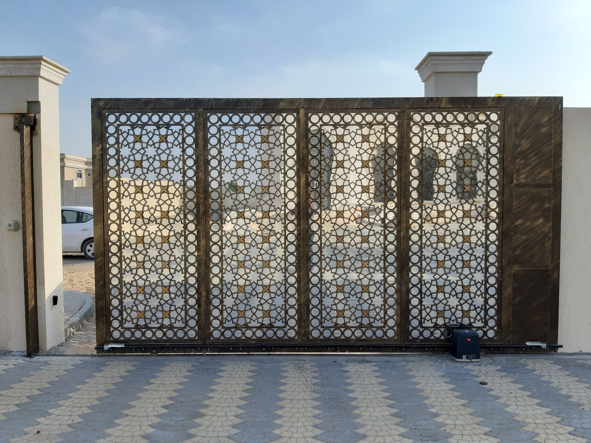 Modern metal driveway gate across a residential entrance with surrounding fencing
